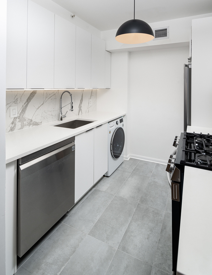 Kitchen after renovation showing contemporary design with white quartz countertops