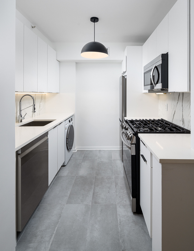 Kitchen after renovation with modern white cabinets and matte black finishes