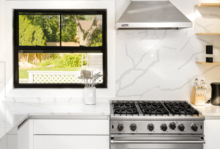 Kitchen island with white marble waterfall counter and recessed LED lights